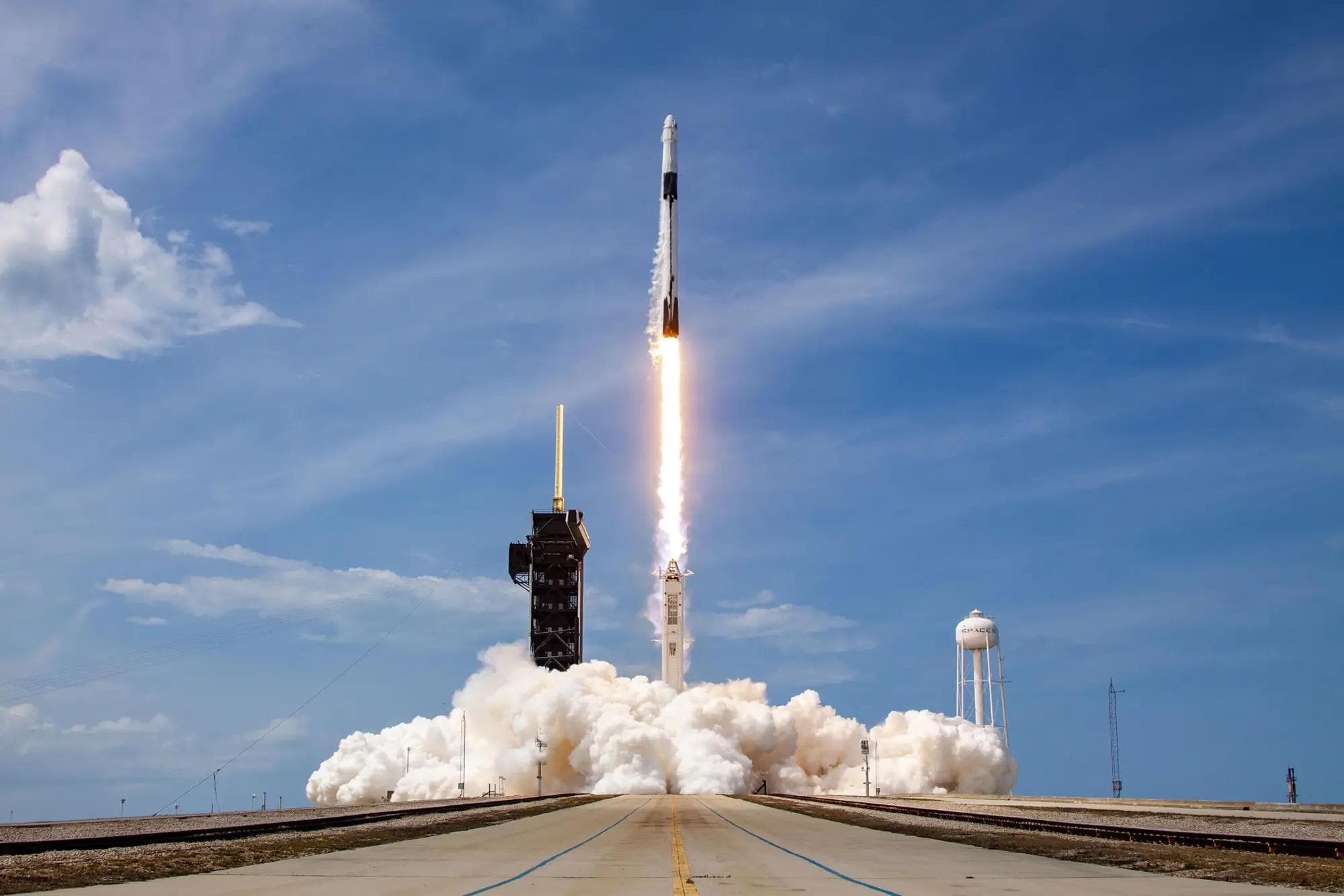 SpaceX Falcon 9 DM-2 mission launching from Kennedy Space Center, vapor trail and exhaust plume against the sky