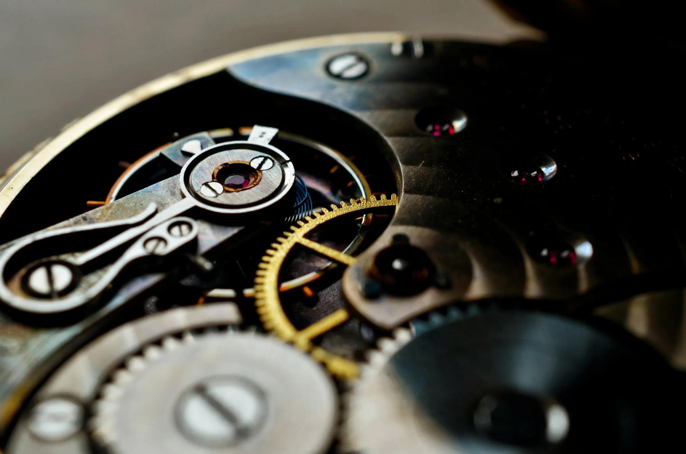 Macro view of a mechanical watch movement showing gears, jewels and a gold escapement wheel