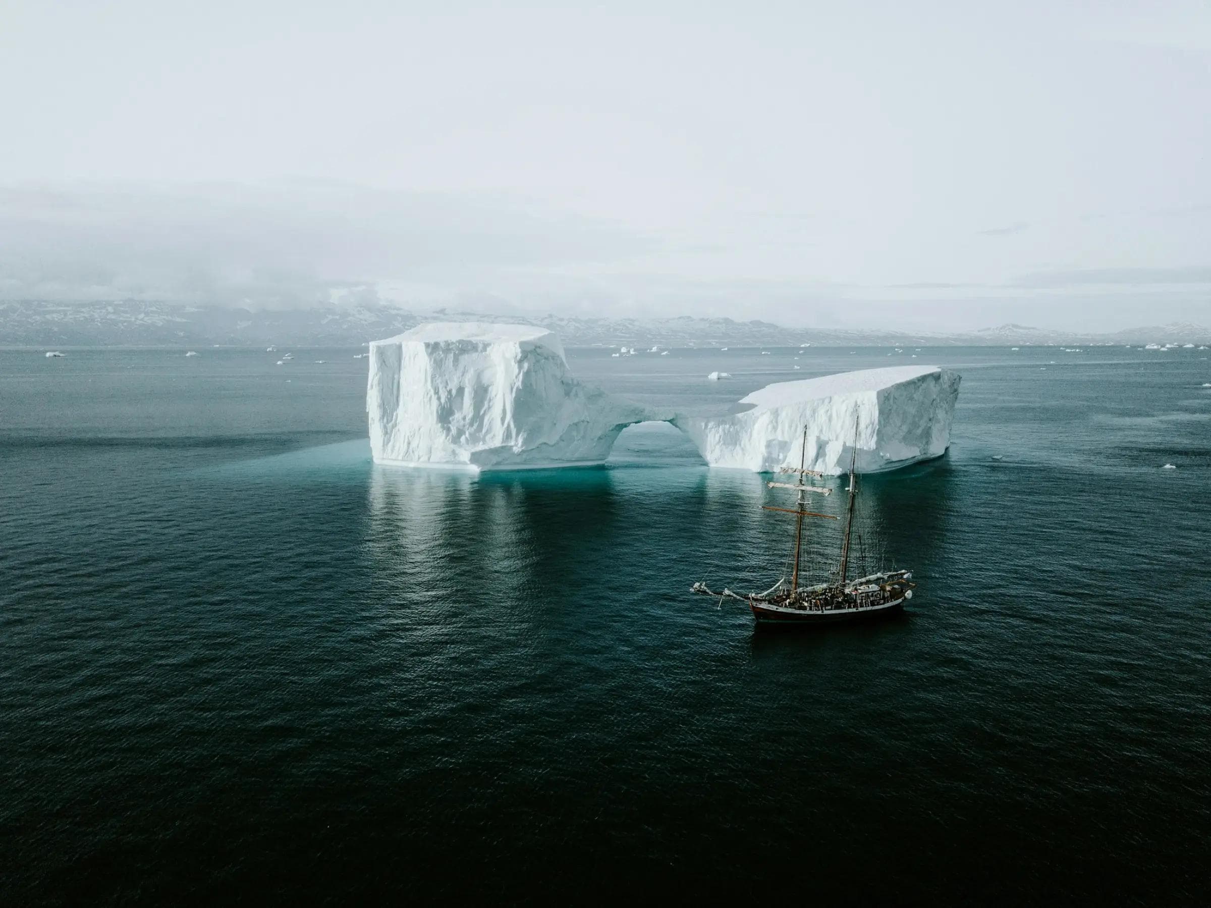 An expedition vessel anchored among Arctic icebergs in remote open water